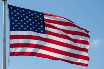 American flag waving on pole against clear blue sky, symbolizing USA manufacturing pride