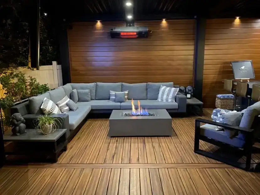 Modern outdoor patio with sectional sofa, fire pit table, and wall-mounted heater on wood deck