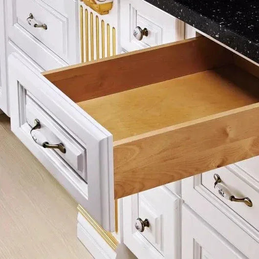 White wooden kitchen drawers with bronze handles and gold detailing, one drawer open showing natural wood interior
