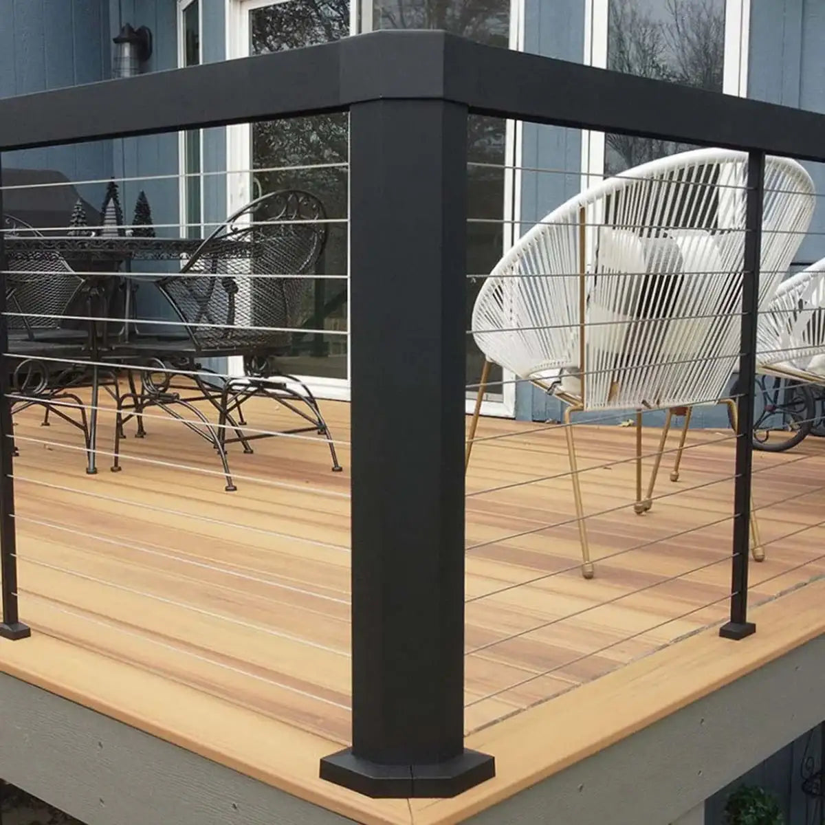 Modern black deck railing with stainless steel cables on wooden patio, outdoor furniture visible