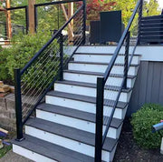 Modern outdoor deck stairs with black cable railings and gray composite treads for residential use
