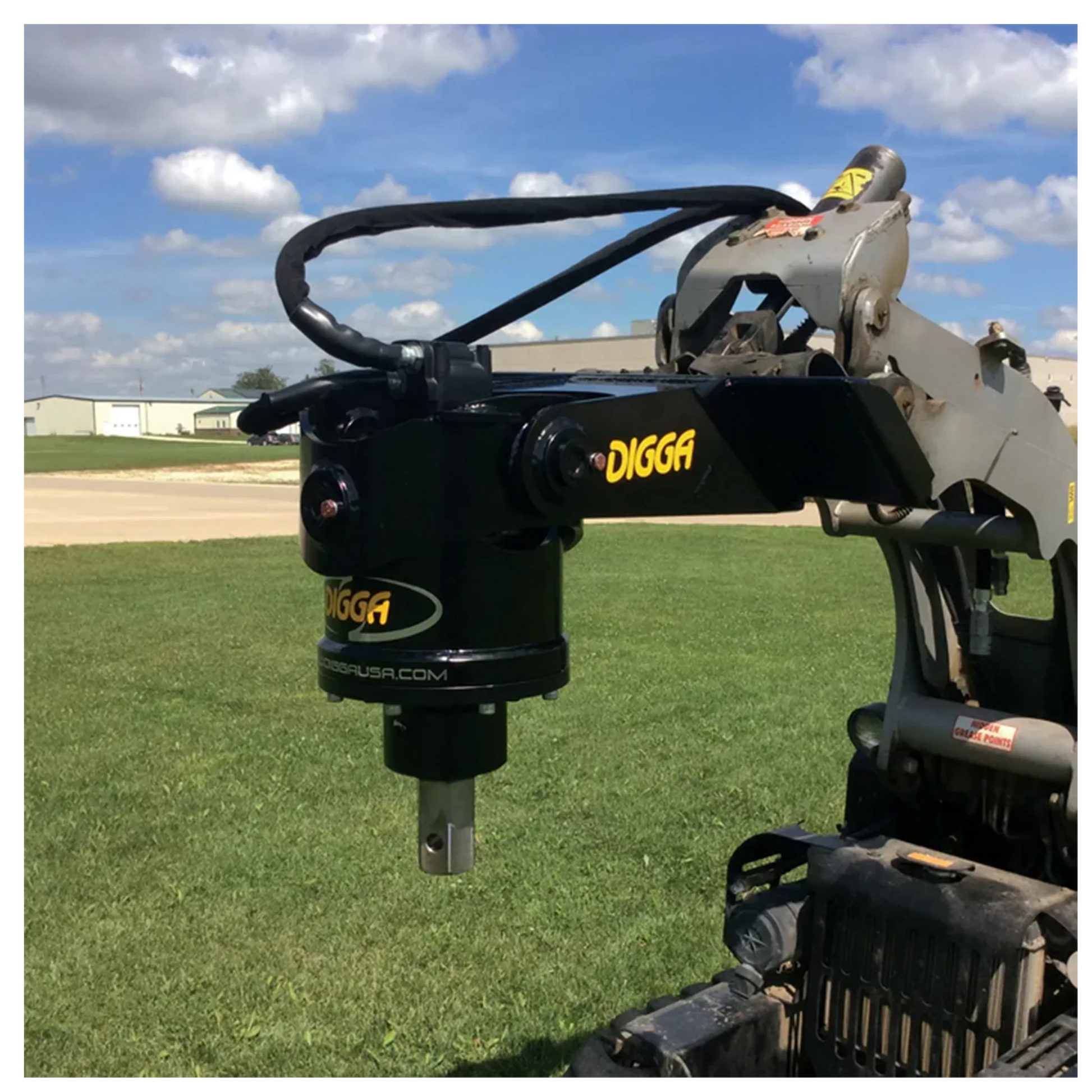 Digga mini skid steer auger drive attachment on construction equipment arm over grass field