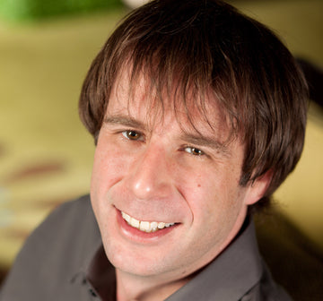 Close-up of a person with brown hair and a gray shirt against a blurred background