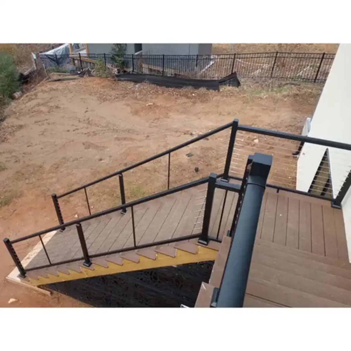 Black metal railing on outdoor wooden deck stairs with yellow safety edge, ideal for industrial or residential use.