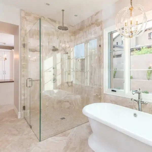 Luxury bathroom with frameless glass shower enclosure, marble tile, freestanding tub, and chandelier lighting