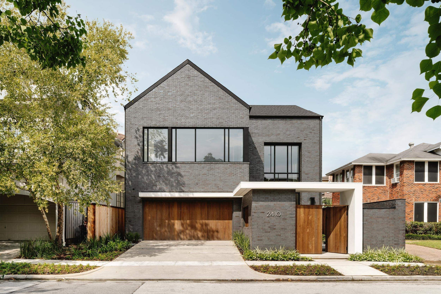Modern gray brick house with wooden garage door and large windows