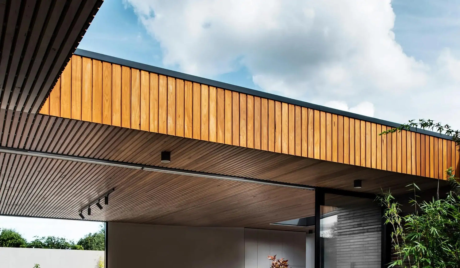 Modern wooden cladding and slatted ceiling on contemporary building exterior under blue sky