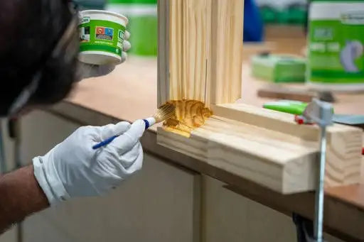 Applying wood finish with brush on lumber in workshop, industrial supplies for manufacturing