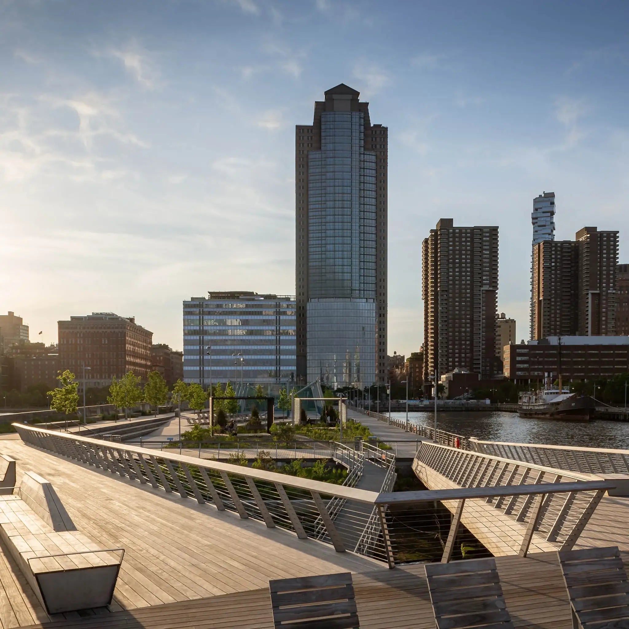 Modern waterfront boardwalk with urban skyline and glass skyscrapers under clear blue sky